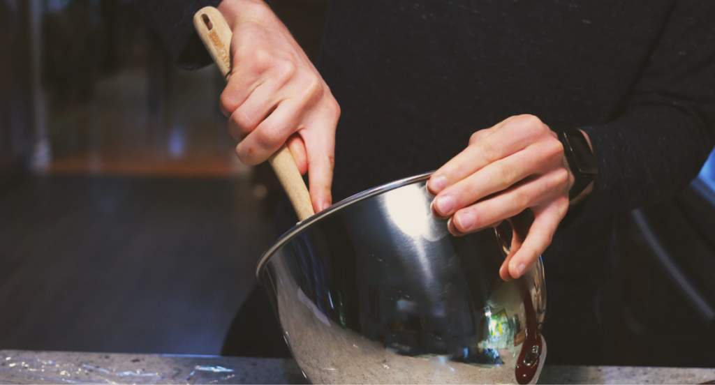 person using a steel mixing bowl to make a cannabis-infused bath bomb