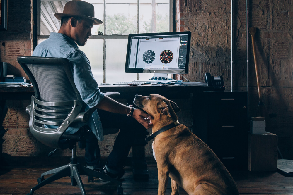 man on the computer in his home office pets his dog