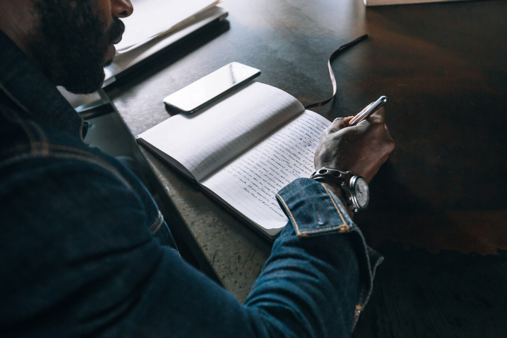 man writes in a journal